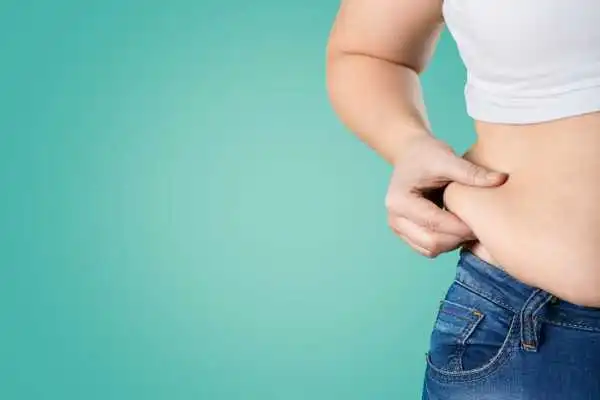 Image of woman pinching her love handles to show weight gain Wisley